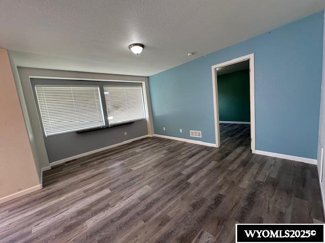 517 Archers Trl, Rock Springs, WY 82901 - unfurnished room with dark wood-type flooring, baseboards, and a textured ceiling