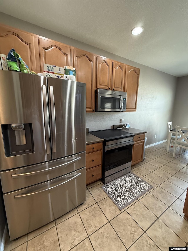 1765 New Mexico St, Green River, WY 82935 - kitchen with appliances with stainless steel finishes, dark countertops, brown cabinets, light tile patterned floors, and recessed lighting