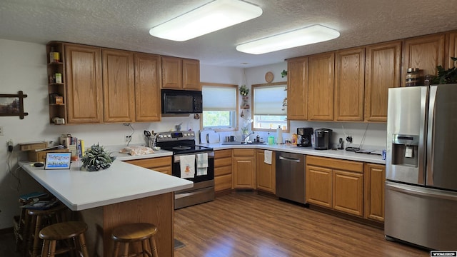190 Ln 7, Thermopolis, WY 82443 - kitchen with appliances with stainless steel finishes, a kitchen breakfast bar, a peninsula, a textured ceiling, and a sink