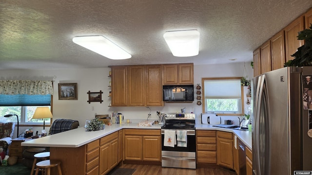 190 Ln 7, Thermopolis, WY 82443 - kitchen with stainless steel appliances, a peninsula, healthy amount of natural light, dark wood finished floors, and a textured ceiling