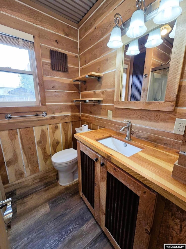 311 3rd St, Ten Sleep, WY 82442 - bathroom featuring vanity, wood finished floors, toilet, wooden walls, and a shower