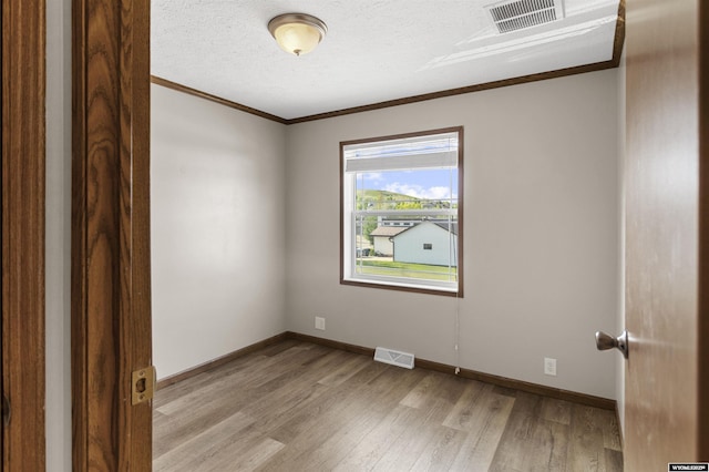 1673 Troy, Kemmerer, WY 83101 - spare room featuring ornamental molding, light wood-style flooring, a textured ceiling, and baseboards