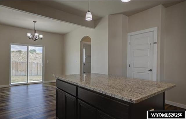 827 Dusty Ter, Mills, WY 82604 - kitchen with arched walkways, baseboards, dark wood finished floors, light stone countertops, and a center island