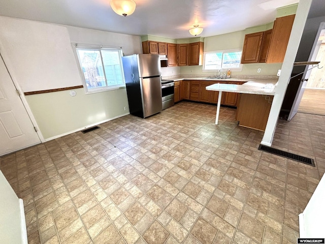 314 S Labarge St, La Barge, WY 83123 - kitchen with stainless steel appliances, a sink, baseboards, light countertops, and brown cabinetry