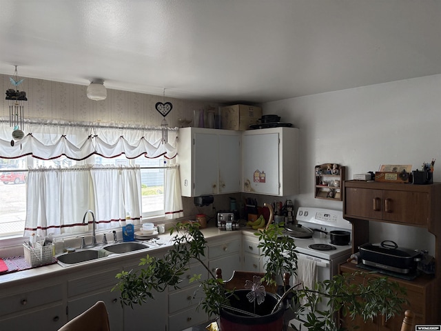 808 E Adams Ave, Riverton, WY 82501 - kitchen with a sink, electric range, white cabinets, and light countertops