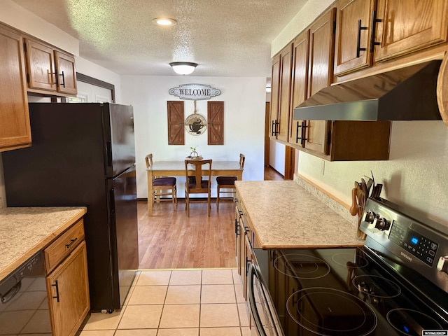 17512 US Highway 14, Carlile, WY 82721 - kitchen with black appliances, light countertops, under cabinet range hood, a textured ceiling, and brown cabinetry