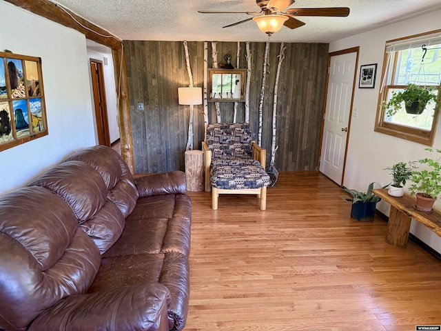 17512 US Highway 14, Carlile, WY 82721 - living room featuring light wood finished floors, a ceiling fan, wood walls, and a textured ceiling