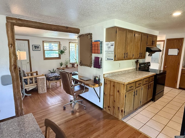 17512 US Highway 14, Carlile, WY 82721 - kitchen featuring black electric range, under cabinet range hood, light countertops, a textured ceiling, and light wood-type flooring