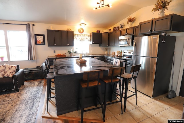 108 Tamari Dr, Buffalo, WY 82834 - kitchen with stainless steel appliances, lofted ceiling, a sink, a breakfast bar, and light tile patterned floors