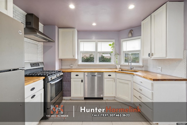 1314 S Wilson St, Casper, WY 82601 - kitchen with butcher block countertops, appliances with stainless steel finishes, a sink, wall chimney exhaust hood, and backsplash