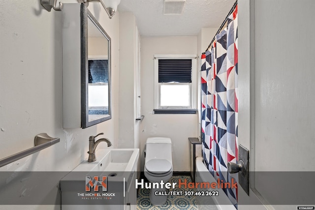 1314 S Wilson St, Casper, WY 82601 - bathroom featuring vanity, a textured ceiling, toilet, and shower / bath combo with shower curtain