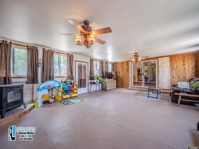 7549 Taxiway, Casper, WY 82604 - sitting room featuring ceiling fan, a wood stove, finished concrete floors, and wood walls