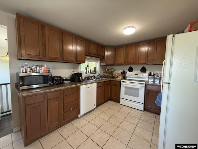 210 N 5th St W, Riverton, WY 82501 - kitchen with white appliances, a sink, light tile patterned floors, dark countertops, and brown cabinetry