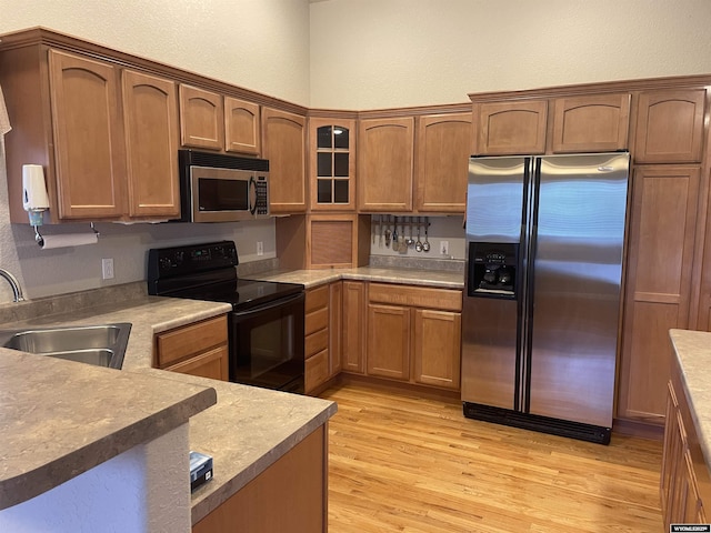 4924 Mountain Way, Casper, WY 82601 - kitchen with stainless steel appliances, light wood-style flooring, glass insert cabinets, brown cabinetry, and light countertops