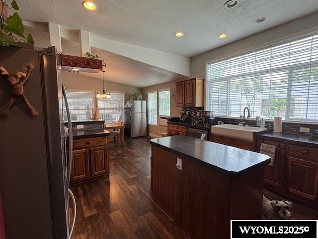 309 Susie Ave, Diamondville, WY 83116 - kitchen featuring appliances with stainless steel finishes, dark countertops, dark wood-style floors, a kitchen island, and a chandelier