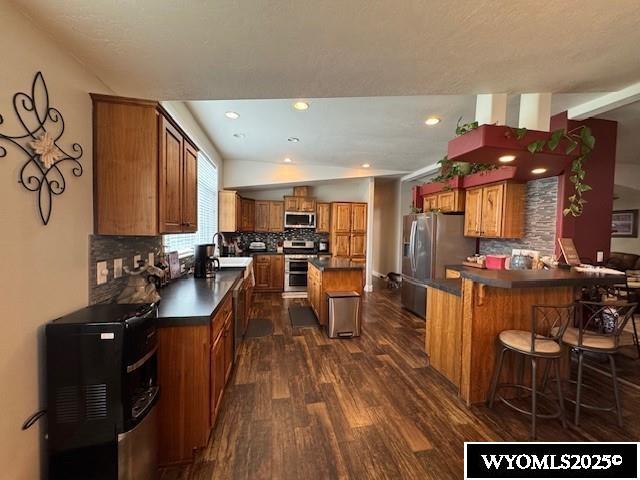309 Susie Ave, Diamondville, WY 83116 - kitchen featuring stainless steel appliances, brown cabinets, dark wood finished floors, dark countertops, and recessed lighting