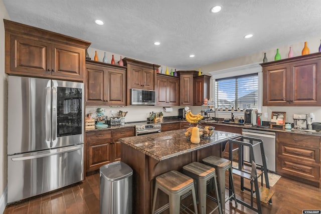 3308 Brickyard Ave, Rock Springs, WY 82901 - kitchen with stainless steel appliances, a textured ceiling, recessed lighting, dark wood-style flooring, and a kitchen breakfast bar