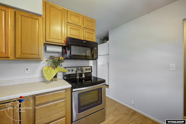 2634 Hanway Ave, Casper, WY 82604 - kitchen featuring black microwave, electric range, light countertops, light wood-type flooring, and freestanding refrigerator