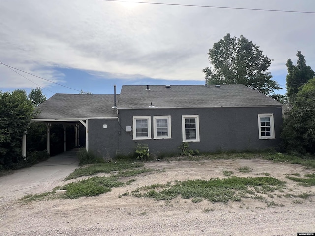 2617 E B St, Torrington, WY 82240 - rear view of house featuring a carport, stucco siding, roof with shingles, and concrete driveway