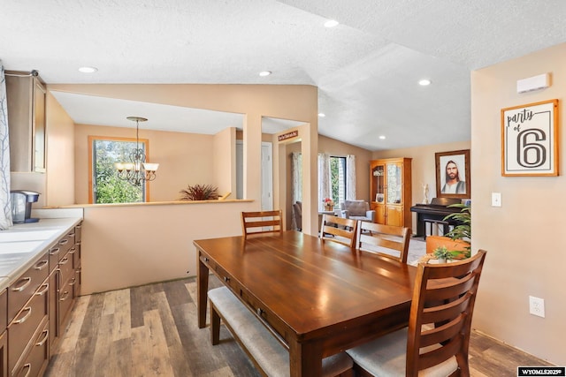 301 Cottonwood St, Evanston, WY 82930 - dining area with a chandelier, wood finished floors, plenty of natural light, vaulted ceiling, and a textured ceiling