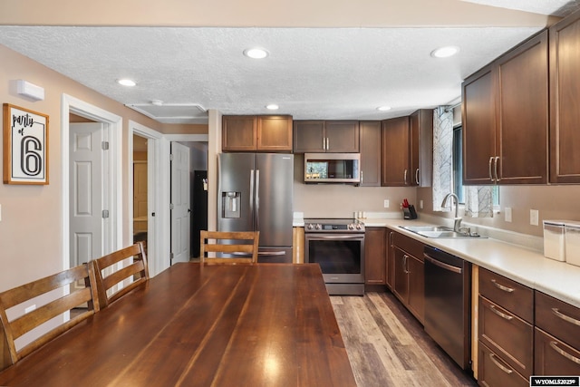 301 Cottonwood St, Evanston, WY 82930 - kitchen with appliances with stainless steel finishes, a textured ceiling, light wood-style floors, dark brown cabinets, and recessed lighting
