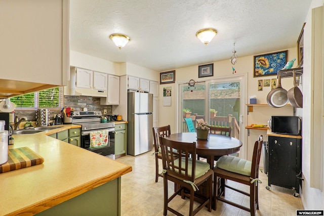 606 Herschler Ave, Evanston, WY 82930 - kitchen with appliances with stainless steel finishes, green cabinets, under cabinet range hood, tasteful backsplash, and light countertops