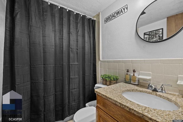 3440 E 18th St, Casper, WY 82609 - bathroom with a textured ceiling, vanity, tile walls, a shower with shower curtain, and wainscoting
