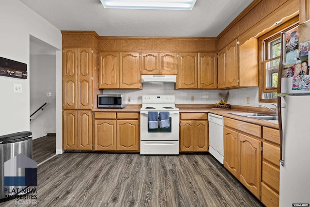 3440 E 18th St, Casper, WY 82609 - kitchen featuring white appliances, under cabinet range hood, dark wood-style flooring, and decorative backsplash