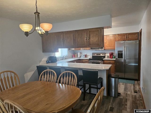 1150 Park View Dr, Green River, WY 82935 - kitchen featuring stainless steel appliances, ventilation hood, dark wood-style floors, light countertops, and pendant lighting