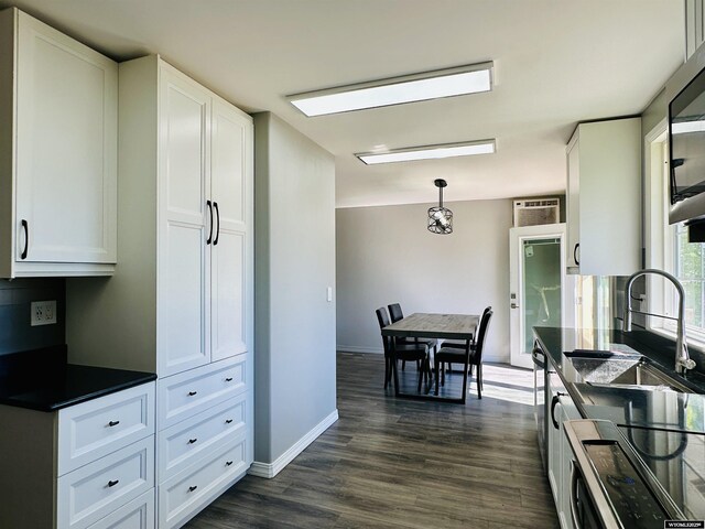 829 Belinda Dr, Riverton, WY 82520 - kitchen with dark countertops, white cabinetry, dark wood finished floors, decorative light fixtures, and stainless steel microwave