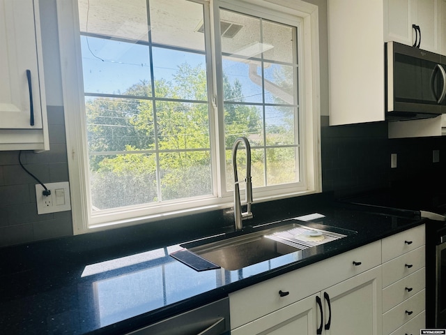 829 Belinda Dr, Riverton, WY 82520 - kitchen with white cabinets, decorative backsplash, dark countertops, and stainless steel dishwasher