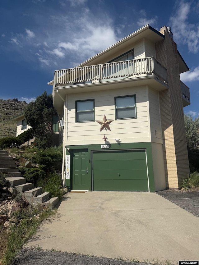 1630 Coulson Dr, Rawlins, WY 82301 - view of front facade with a garage, a balcony, concrete driveway, and a chimney