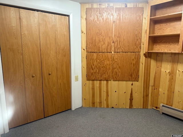 1630 Coulson Dr, Rawlins, WY 82301 - unfurnished bedroom featuring carpet floors, wooden walls, a baseboard radiator, and a closet