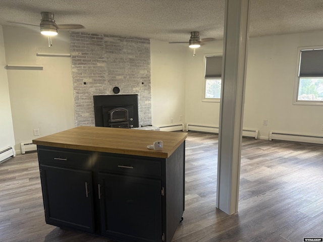 1630 Coulson Dr, Rawlins, WY 82301 - kitchen featuring ceiling fan, butcher block counters, dark cabinetry, a wood stove, and a textured ceiling