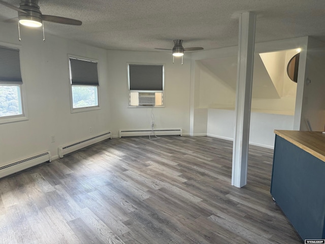 1630 Coulson Dr, Rawlins, WY 82301 - unfurnished room featuring a ceiling fan, a baseboard heating unit, wood finished floors, cooling unit, and a textured ceiling