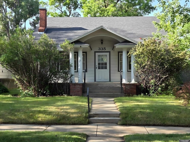 335 E 11th St, Casper, WY 82601 - view of front facade with a chimney, a front lawn, a shingled roof, and a porch