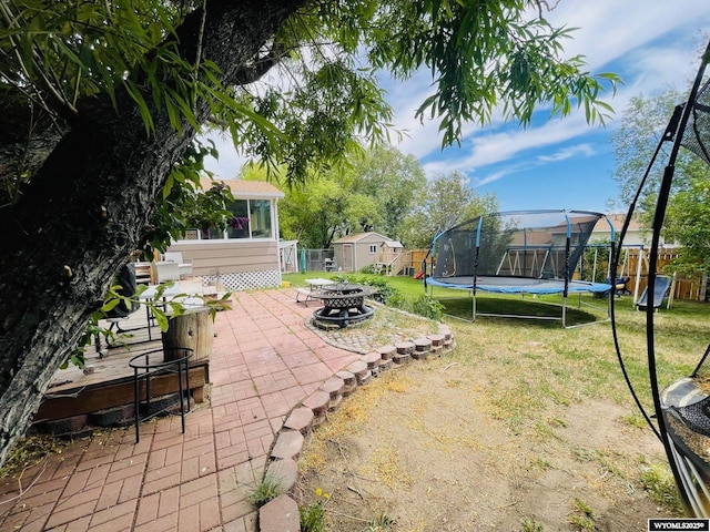 1328 Canyon Ct, Kemmerer, WY 83101 - view of yard featuring a trampoline, a fire pit, a storage unit, and a patio
