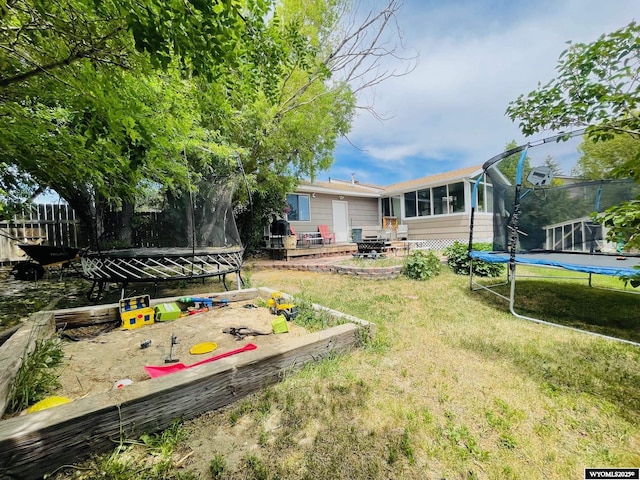 1328 Canyon Ct, Kemmerer, WY 83101 - view of grassy yard with a trampoline, a patio area, and a sunroom
