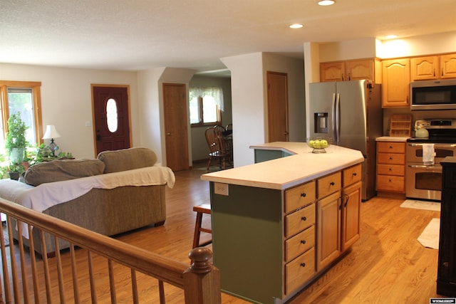 1540 Manor Dr, Casper, WY 82609 - kitchen featuring appliances with stainless steel finishes, light countertops, light wood-type flooring, a kitchen island, and a kitchen bar