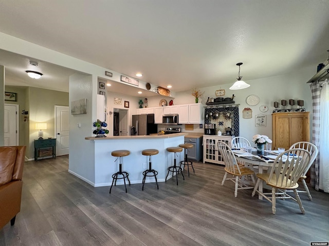 1261 Meadow Ln, Douglas, WY 82633 - kitchen featuring stainless steel microwave, refrigerator with ice dispenser, dark wood-style flooring, a breakfast bar, and white cabinetry