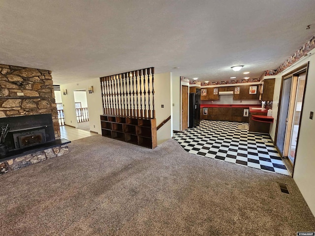 918 E 27th Ave, Torrington, WY 82240 - unfurnished living room featuring a textured ceiling, tile patterned floors, carpet flooring, and a fireplace