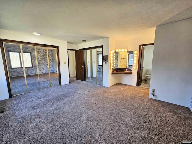 918 E 27th Ave, Torrington, WY 82240 - unfurnished bedroom with carpet floors, two closets, and ensuite bathroom