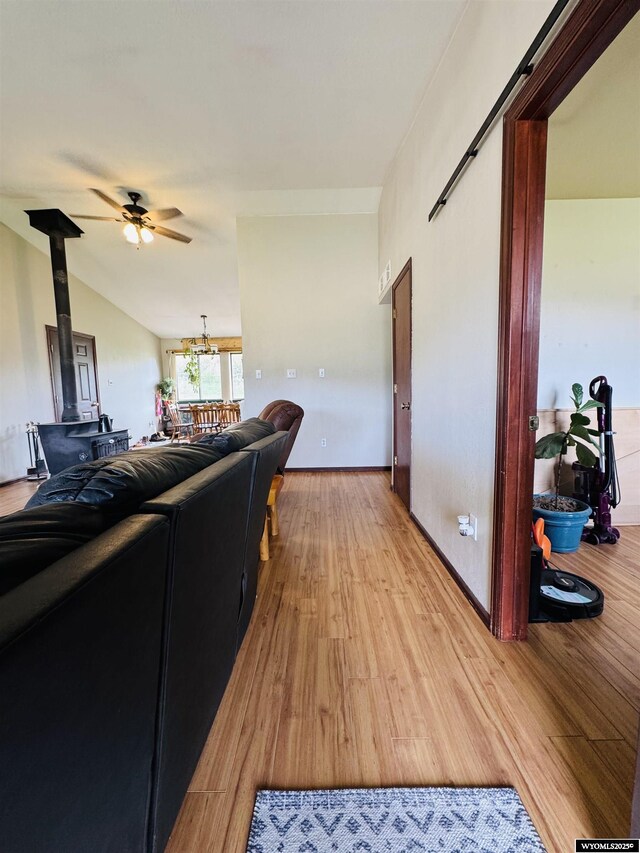 1512 Highview Dr, Dubois, WY 82513 - living area featuring a wood stove, ceiling fan, light wood-style floors, a chandelier, and lofted ceiling