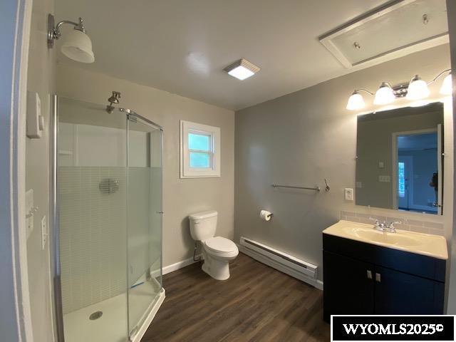 1041 S Mckinley St, Casper, WY 82601 - bathroom featuring a baseboard heating unit, vanity, a shower stall, and wood finished floors