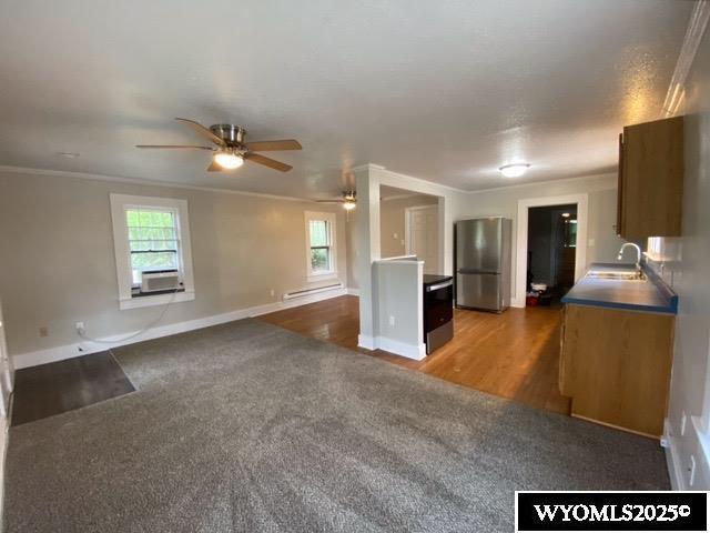 1041 S Mckinley St, Casper, WY 82601 - unfurnished living room featuring ceiling fan, a baseboard heating unit, ornamental molding, cooling unit, and wood finished floors