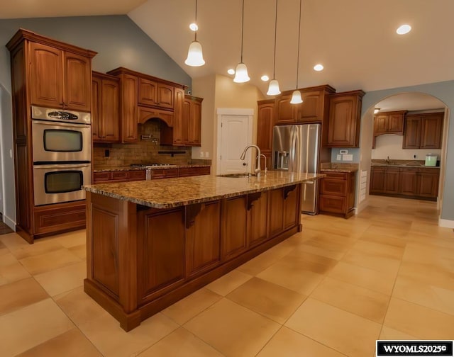 1011 Heritage Cove Dr, Lyman, WY 82937 - kitchen with stainless steel appliances, arched walkways, vaulted ceiling, tasteful backsplash, and a breakfast bar area