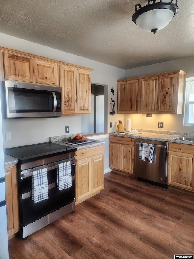 828 Fort St, Buffalo, WY 82834 - kitchen featuring appliances with stainless steel finishes, dark wood-type flooring, a textured ceiling, light brown cabinetry, and light countertops