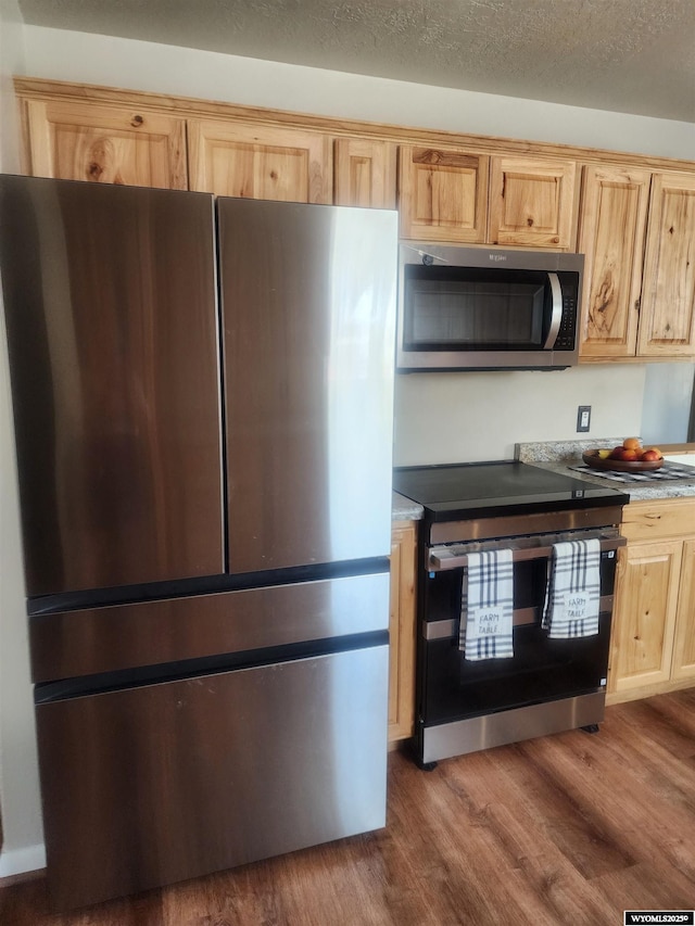 828 Fort St, Buffalo, WY 82834 - kitchen with appliances with stainless steel finishes, wood finished floors, light brown cabinetry, and light countertops