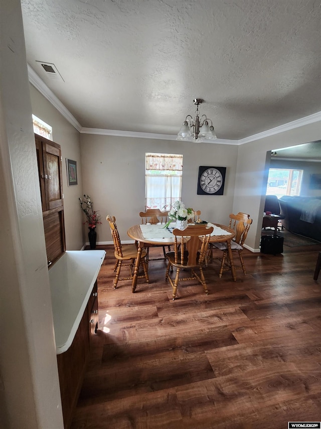 828 Fort St, Buffalo, WY 82834 - dining area featuring dark wood-type flooring, ornamental molding, a textured ceiling, and a chandelier