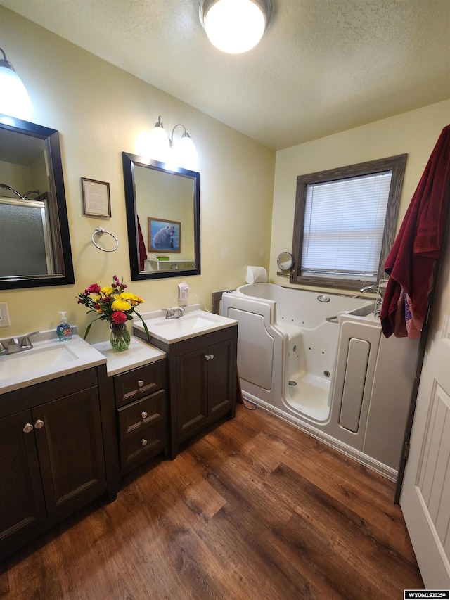 828 Fort St, Buffalo, WY 82834 - bathroom featuring wood finished floors, vanity, a textured ceiling, and a whirlpool tub